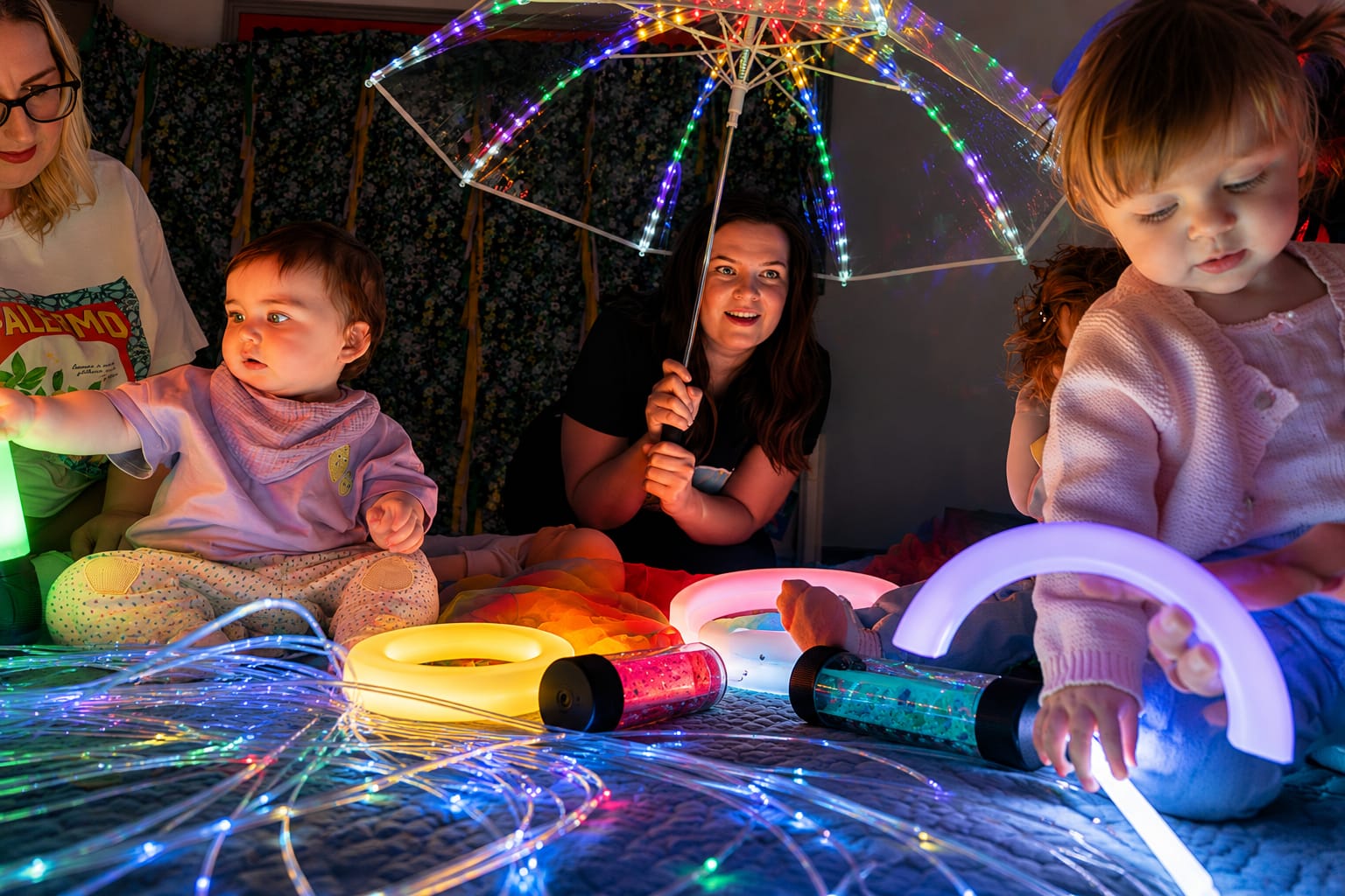 Babies and parents exploring fibre-optic sensory lights and glowing toys at a Baby Babble NI sensory class