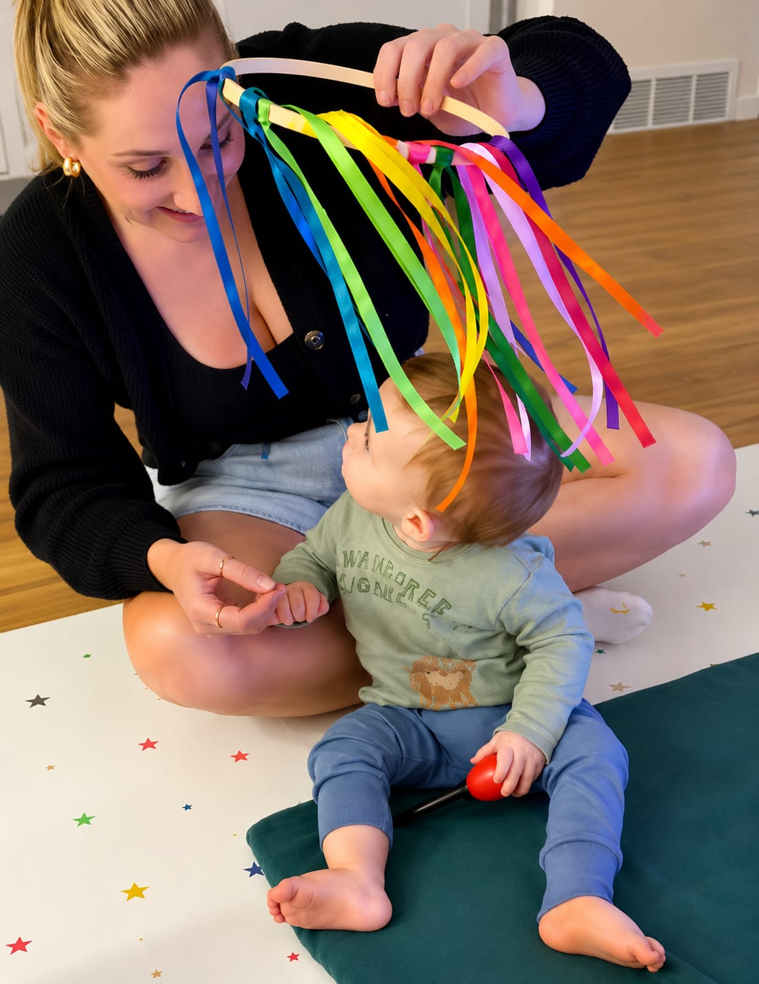 Baby reaching for colourful rainbow ribbons at a Baby Babble NI class
